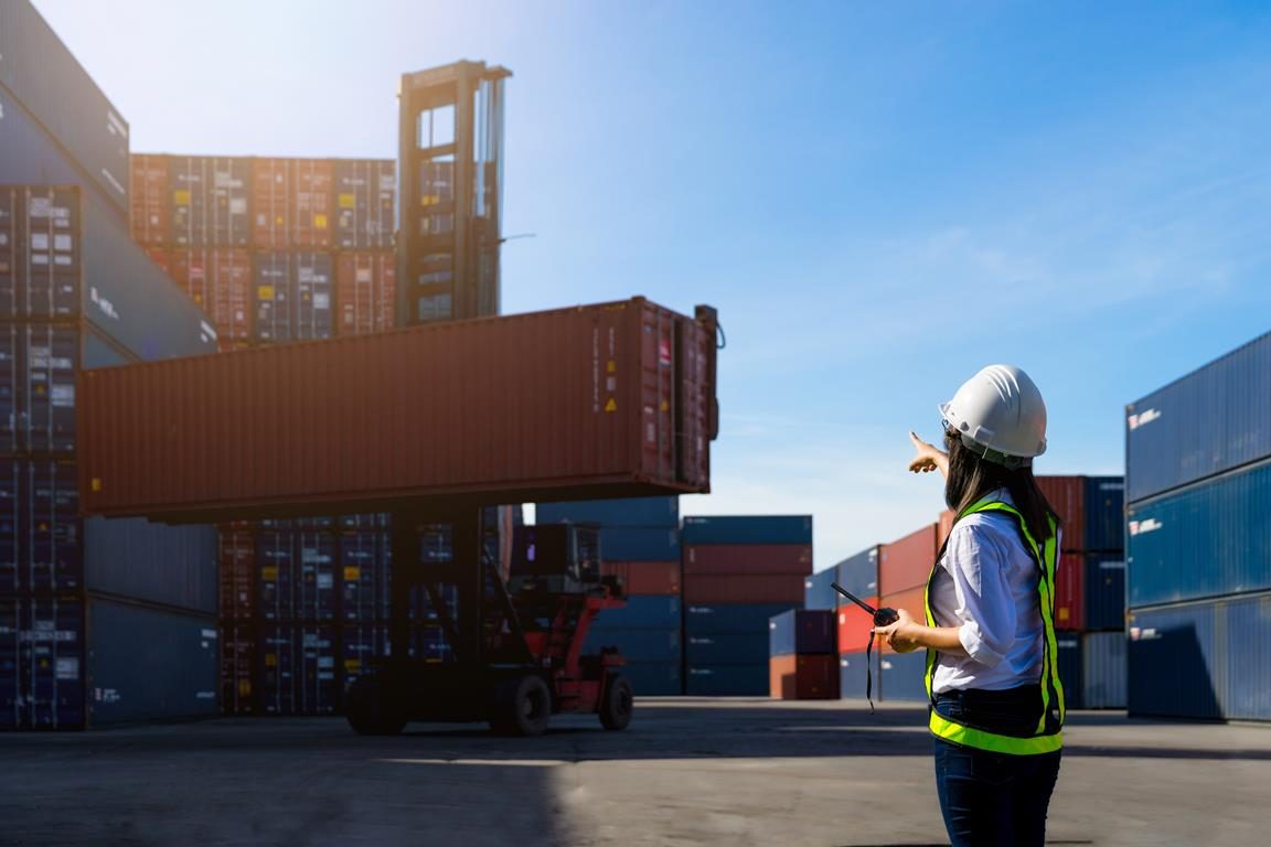 Inspektorin mit Schutzhelm bei der Prüfung im Containerhafen
